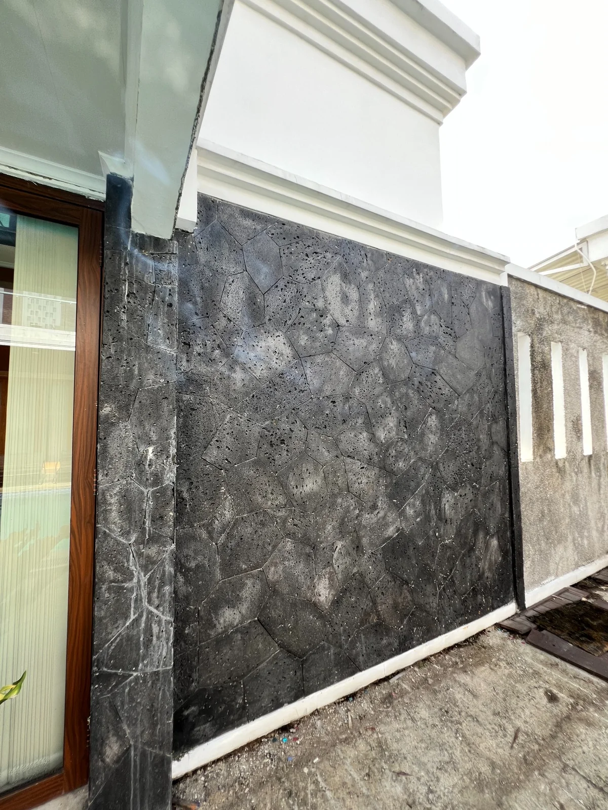 Dinding fasad rumah dengan pemasangan batu templek hitam